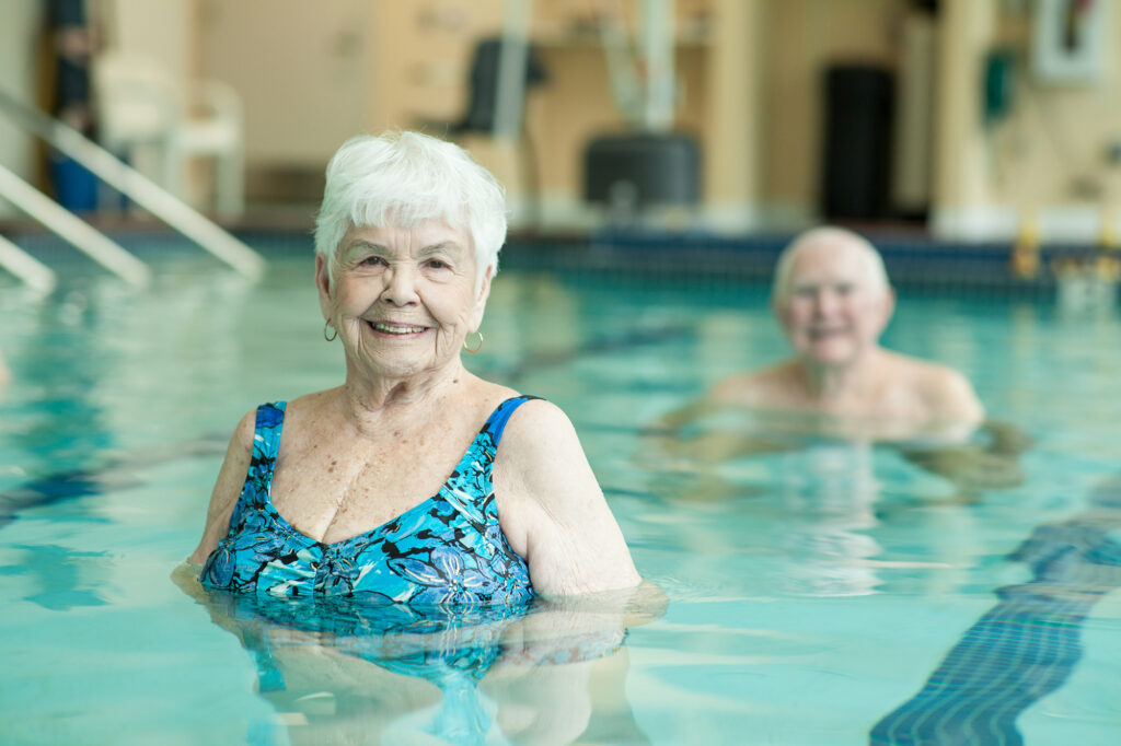 Elderly woman and man in swimming pool. Learn about the difference between nursing homes, senior homes, and retirement homes.
