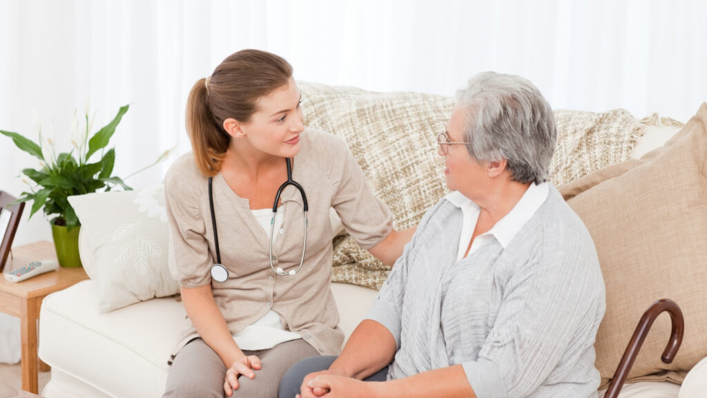 Senior receiving geriatric care from nurse on couch
