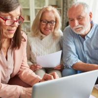 Three seniors researching on the computer. Choosing the right senior memory care
